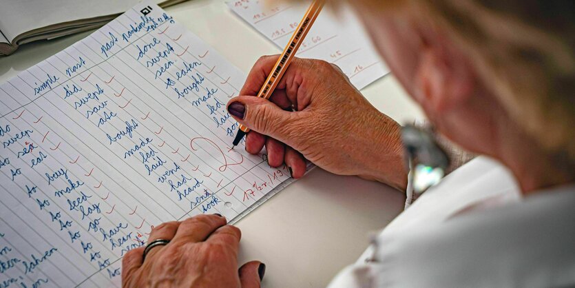 Lehrerin korrigiert mit Rotstift Klassenarbeiten