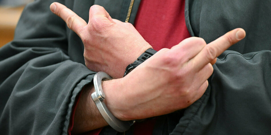 Angeklagter in Handschellen zeigt zwei Stinkefinger