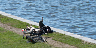 Paar und Fahrrad liegen am Spreeufer