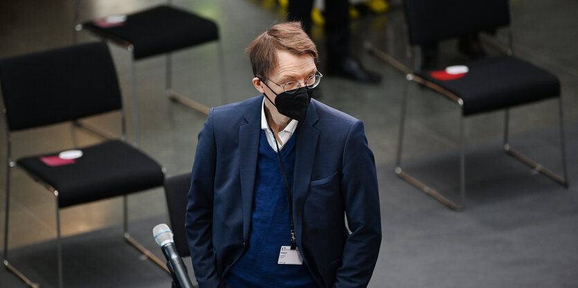 Karl Lauterbach mit Maske steht in einem Raum mit Stühlen