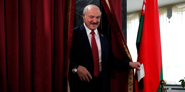 Lukaschenko tritt mit Wahlzettel aus der Wahlkabine