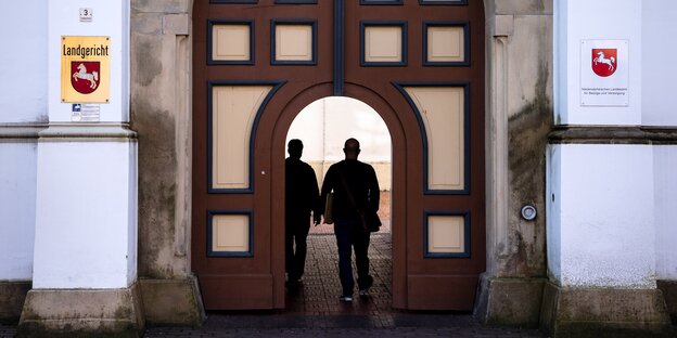 Zwei Leute betreten den Innenhof des Landgerichts Aurich.