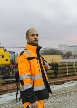 Ein Mann in Arbeitskleidung steht auf einer Baustelle Ein Mann in Arbeitskleidung steht auf einer Baustelle