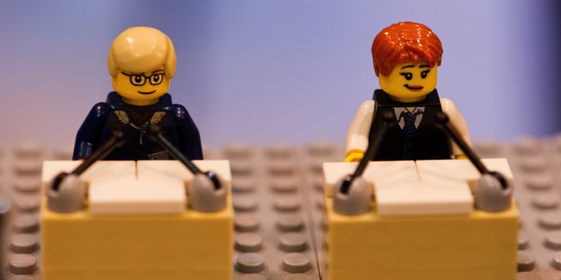 Zwei Legofiguren, die jeweils vor einem Podium stehen.