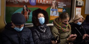 Drei Frauen und ein Mann sitzen in einer U-Bahn, eine starrt zur Decke, die anderen gucken auf ihre Smartphones
