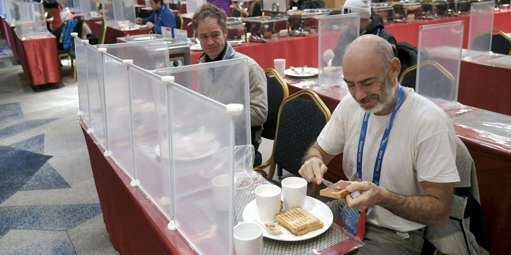 Hotelgäste beim Essen hinter Plexiglas