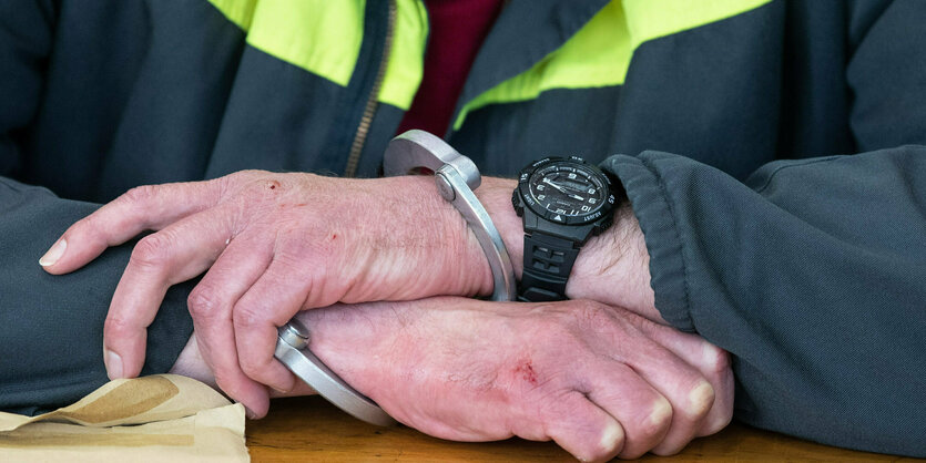 Angeklagter sitzt sitzt in Handschellen auf der Anklagebank.