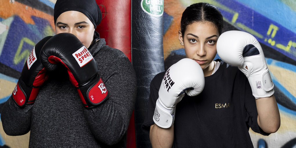 Zwei Frauen mit Boxhandschuhen stehen sich in kampfbereiter Position gegenüber