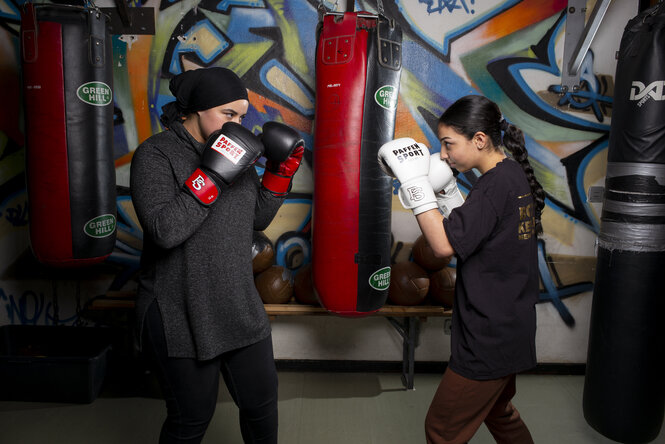 Zwei Frauen mit Boxhandschuhen stehen sich in kampfbereiter Position gegenüber