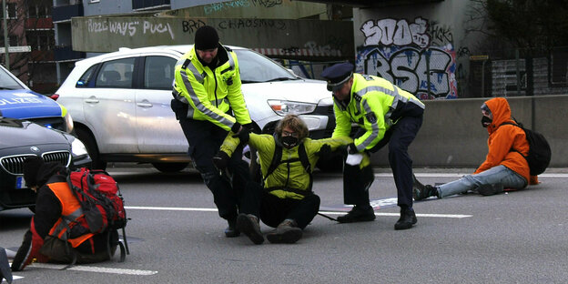 Polizisten ziehen Blockierer von der Straße