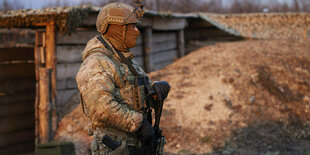 Bewaffneter Soldat vor einem Sandhaufen