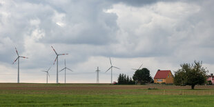 Windräder auf Acker vor kleinem Haus