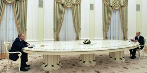 Präsident Putin und Bundeskanzler Scholz an einem langen Tisch.