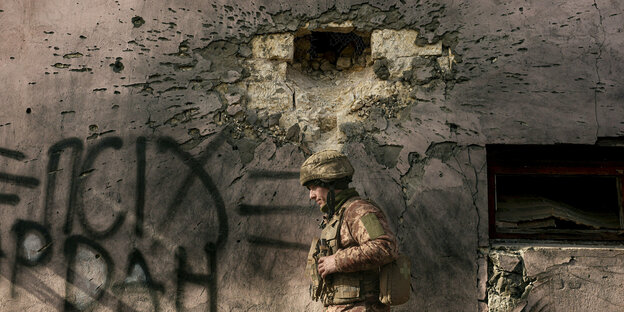 Ein Soldat vor einer Mauer mit einem großen Einschussloch Ein Soldat vor einer Mauer mit einem großen Einschussloch