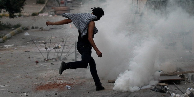 Ein Demonstrant in Istanbul versucht eine Sprühdose von sich weg zu treten