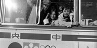 Aus einem Bus mit der Aufschrift "Sapporo '72" schauen deutsche Sportlerinnen heraus.