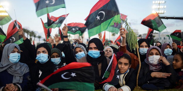 Libische Frauen und Kinder schwenken rot-schwarz-grüne Nationalflaggen