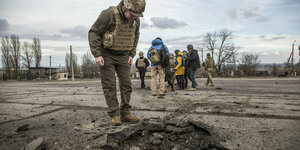 Soldat beugt sich über Krater in Boden
