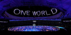 Ein Feuerwerk über einem Sportstadion bildet den Schriftzug "One World"