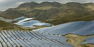 Solarpanels ziehen sich über grün bewachsene Hügel