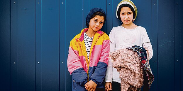Die Mädchen Zainab (12 Jahre r.) und Nida (11) vor der Wand eines Wohncontainers