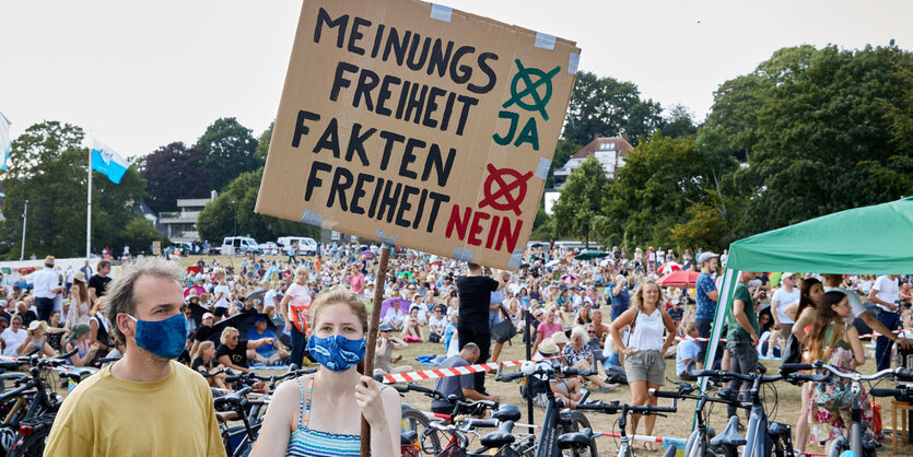 Teilnehmende einer Demonstration halten ein Plakat mit der Aufschrift "Meinungsfreiheit Ja, Faktenfreiheit Nein" in die Höhe