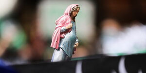 DemonstrantInnen halten eine Figur hoch, die eine die heilige schwangere Maria zeigen soll