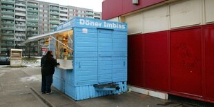 hellblauer container steht als Dönerr Imbiss zwischen Hochhäusern