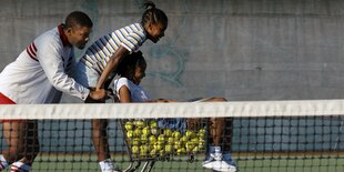 Richard Williams schiebt Venus und Serena Williams in einem Einkaufswagen mit Tennisbällen.