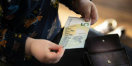 Ein kleines Kind hält einen %-Euro Schein in der Hand