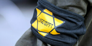 Ein Teilnehmer trägt eine Armbinde mit einem gelben Stern, der an einen Judenstern erinnern soll, mit der Aufschrift «Ungeimpft».