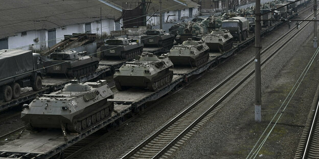 Zugwaggons mit Panzern beladen in einem Bahnhof.