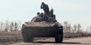 ein Panzer mit zwei Soldaten steht am Straßenrand