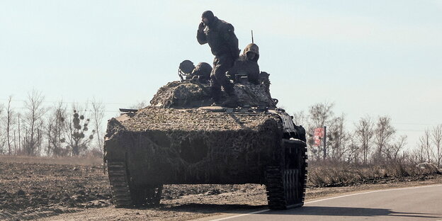 ein Panzer mit zwei Soldaten steht am Straßenrand