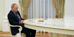 Wladimir Putin sitzt an einem Ende eines weißen Tisches