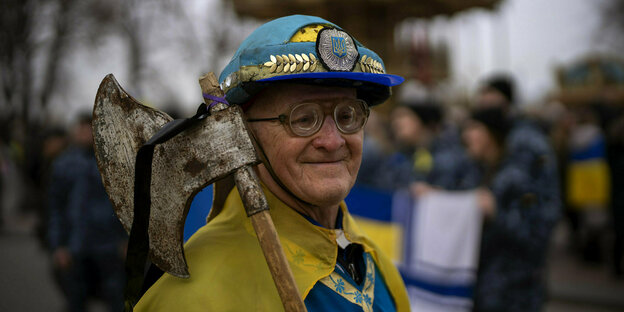 Ein alter Mann, in den Farben der Ukraine gewandet und einer Axt über der Schulter