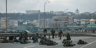Soldaten mit Gewehren liegen unter der Leitplanke einer Schnellstraße.