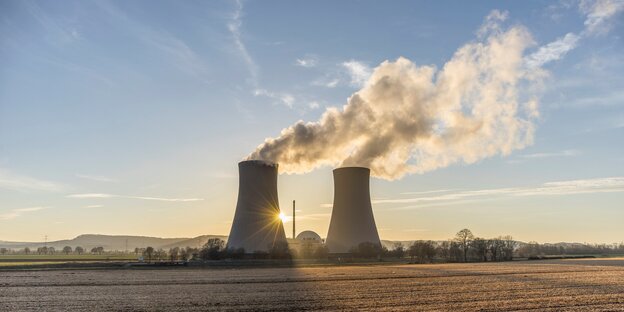 Zwei Kühltürme eines Atomkraftwerkes stehen auf einem Feld