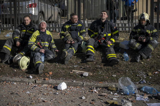 Feuerwehrmänner sitzen am Strassenrand mit Wasserflaschen