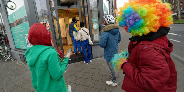 Frauen in verschiedenen Kostümen warten vor einem Testzentrum in Köln