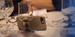 Ein Smartphone ist gegen ein Glas gelehnt