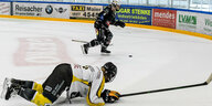 Eine Eishockeyspielerin liegt in der Partie auf dem Eis, eine andere läuft im Hintergrund