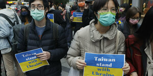 Demonstranten mit blau-gelben Schildern Taiwan steht der Ukraine bei.