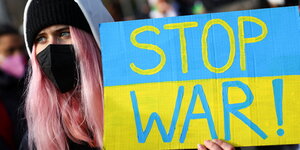 Eine Frau hält ein Anti-Kriegs-Plakat in der Hand