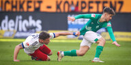 Ein Spieler des HSV zieht im Fallen am Trikot eines Spielers von Werder Bremen