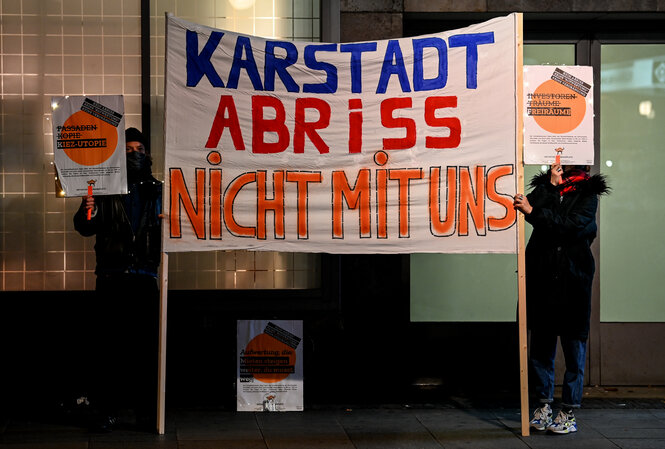 Ein Mensch protestiert mit einem Plakat gegen den Abriss von Karstadt