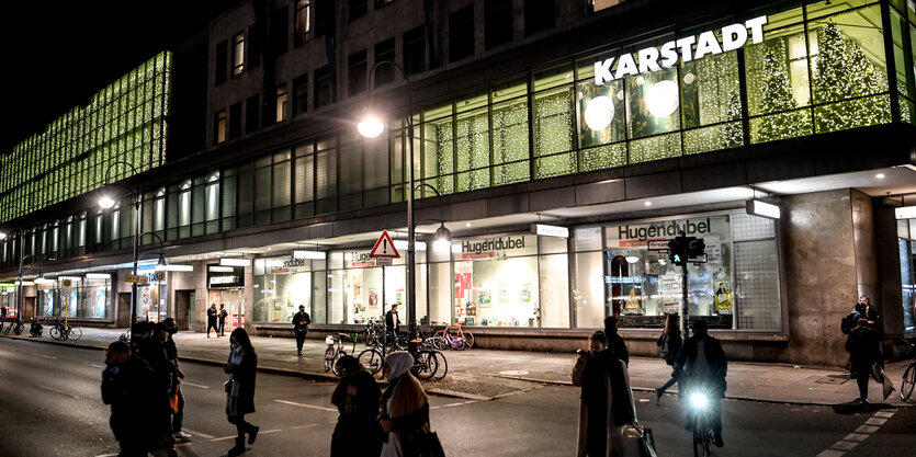 Im Dunkeln laufen Menschen am Karstadt vorbei