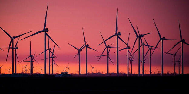 Windkraftanlagen stehen in einem Windpark im Sonnenaufgang.