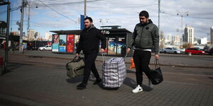 Zwei Männer schleppen Gepäck zum Bahnhof
