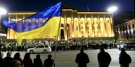 Ein Demonstrant schwenkt die blau-gelbe ukrainische Fahne vor dem Parlamentsgebäude in Tiflis